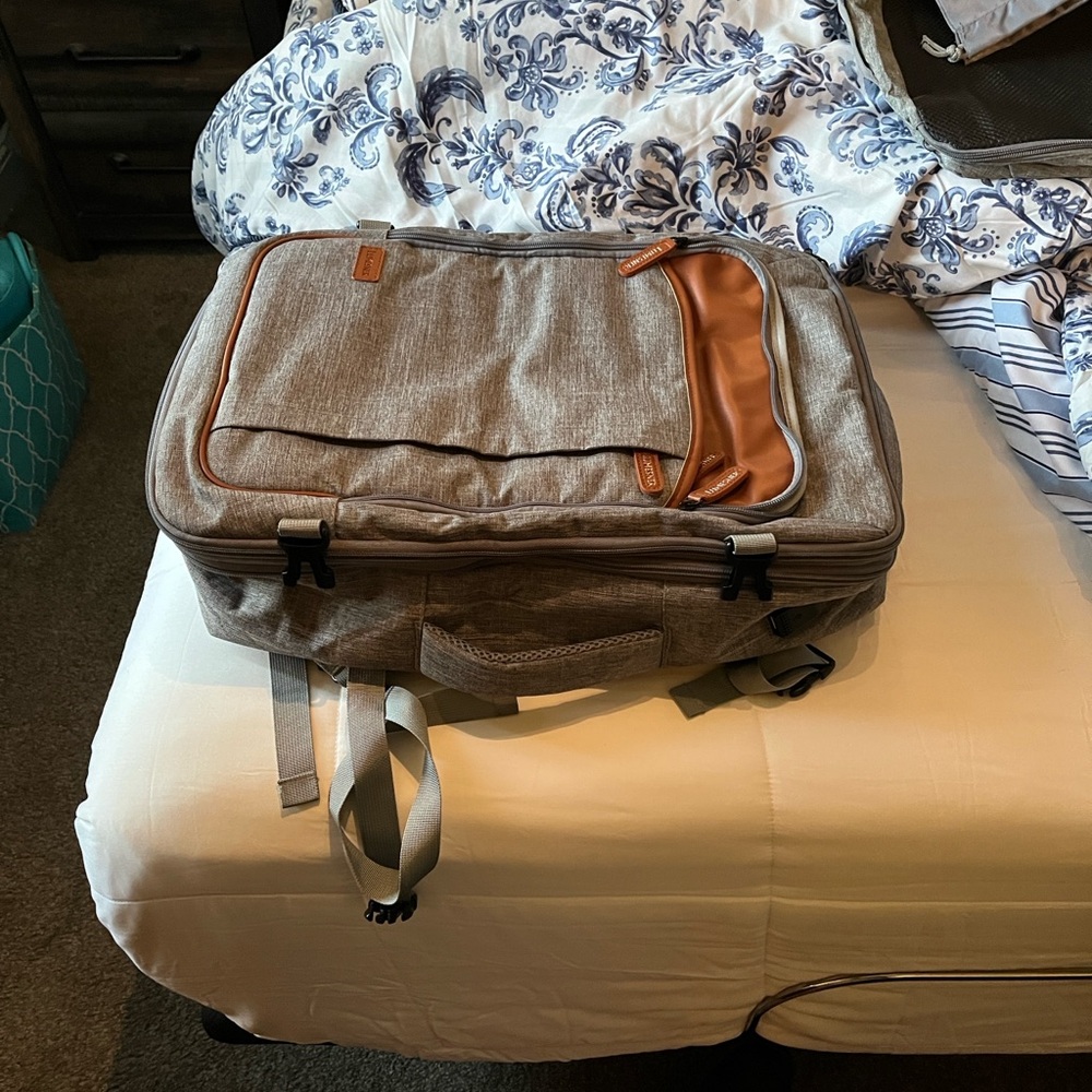 Gray and Brown Backpack with top and side handles for travel.